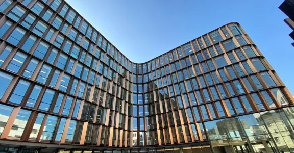 Bâtiment en bois et verre, mélangeant modernité et nature, offrant une ambiance chaleureuse et lumineuse.