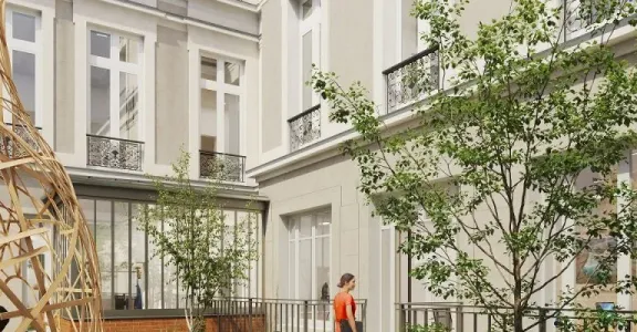 Une cour avec un arbre au milieu et un bâtiment en arrière-plan.