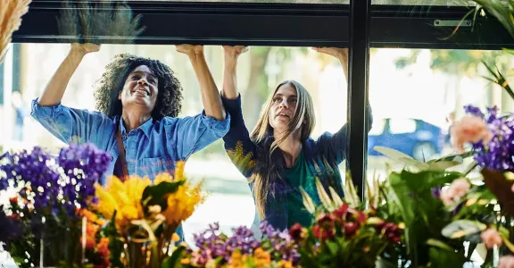 Deux femmes regardant par une fenêtre des fleurs colorées en fleurs.